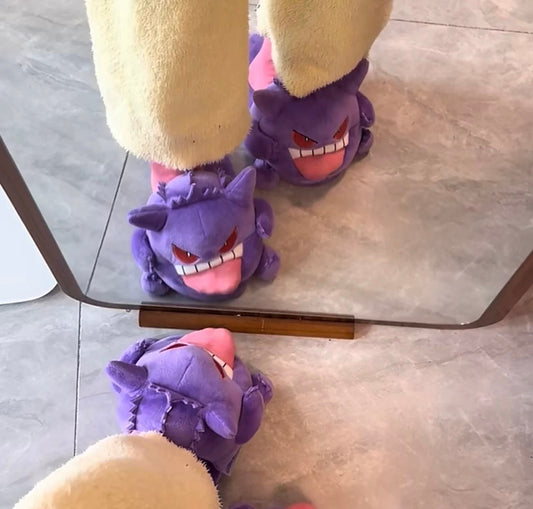 Purple slippers with cartoon face design worn by a person on a glass table.